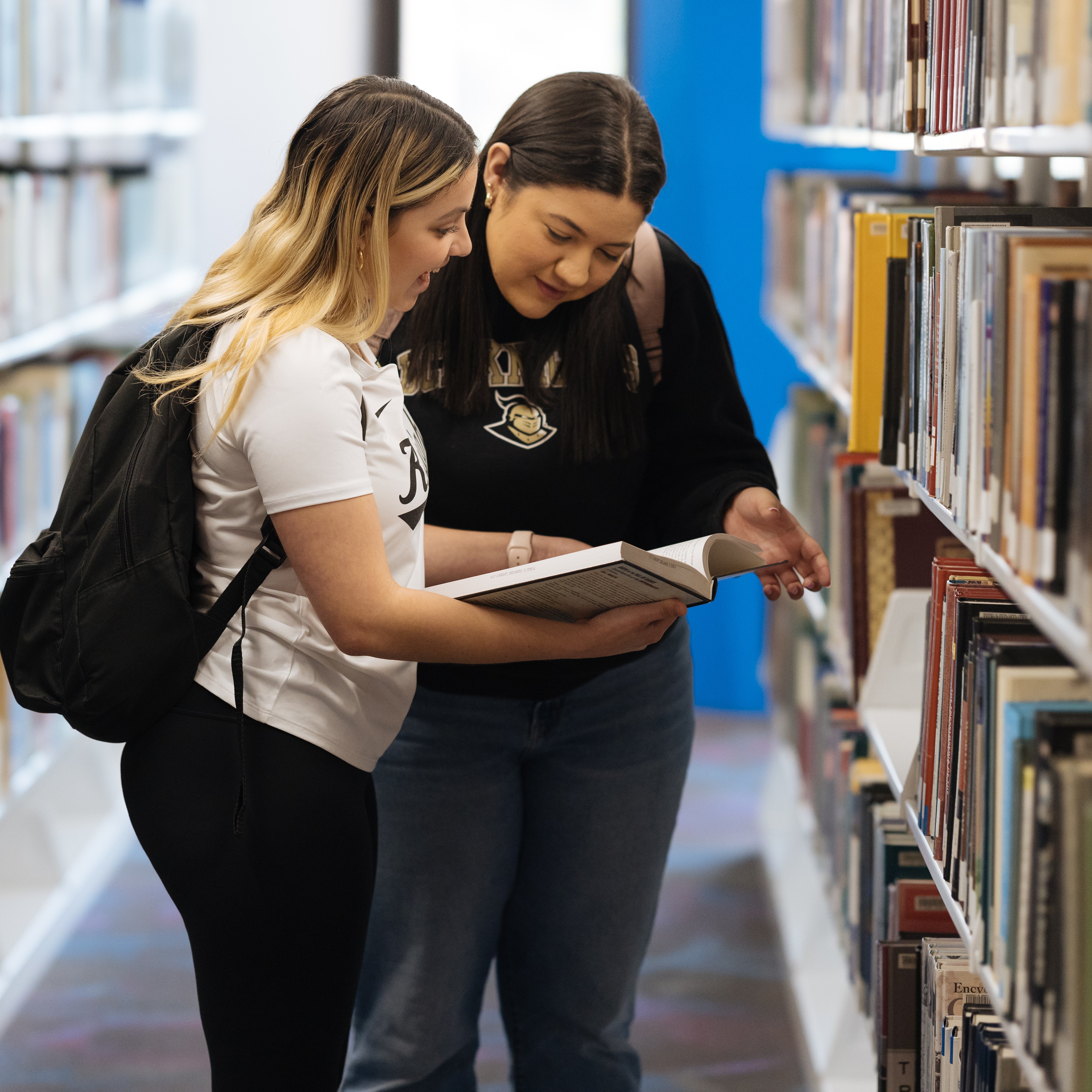 Two students look at a book in the John C. Hitt Library.