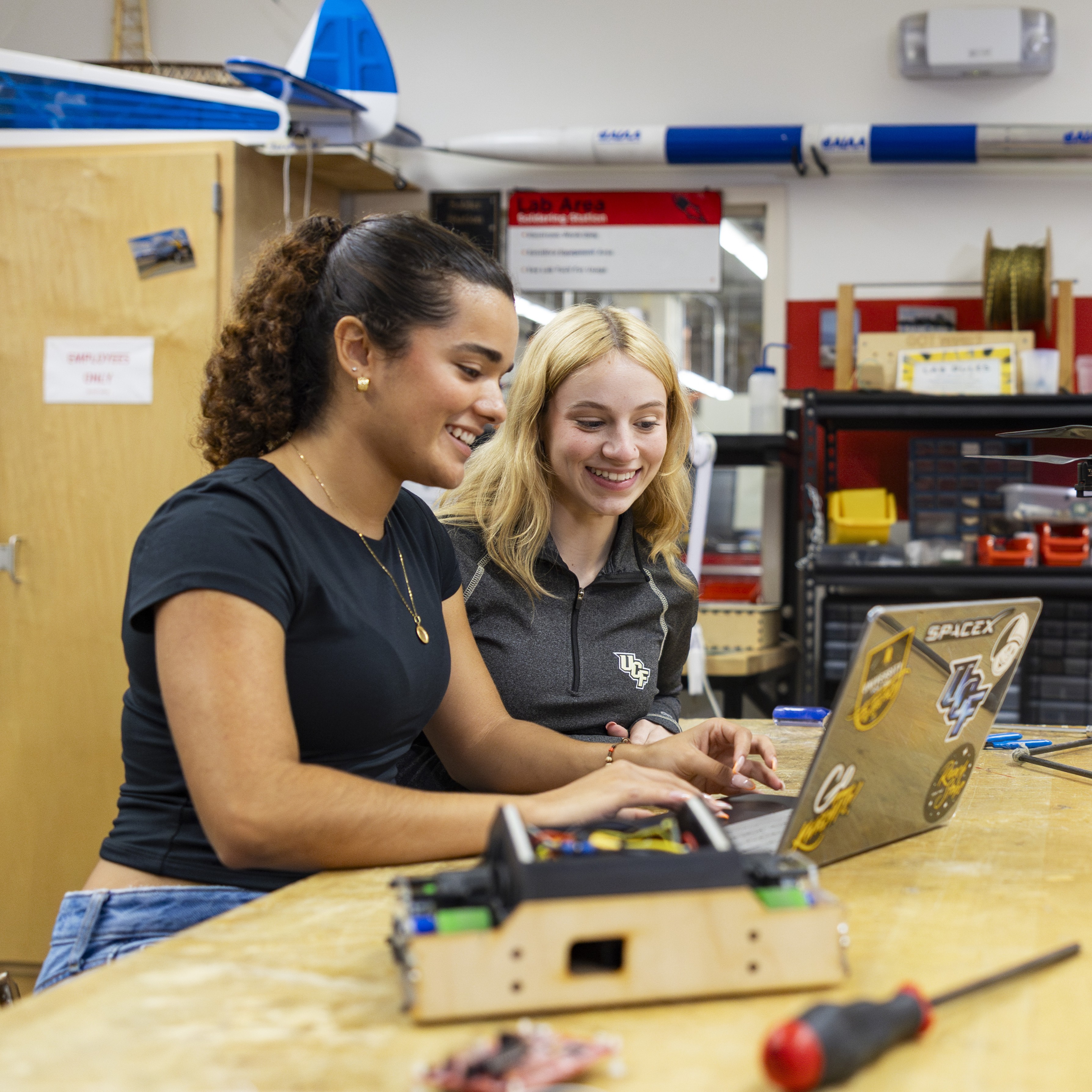 Two students look at a laptop.