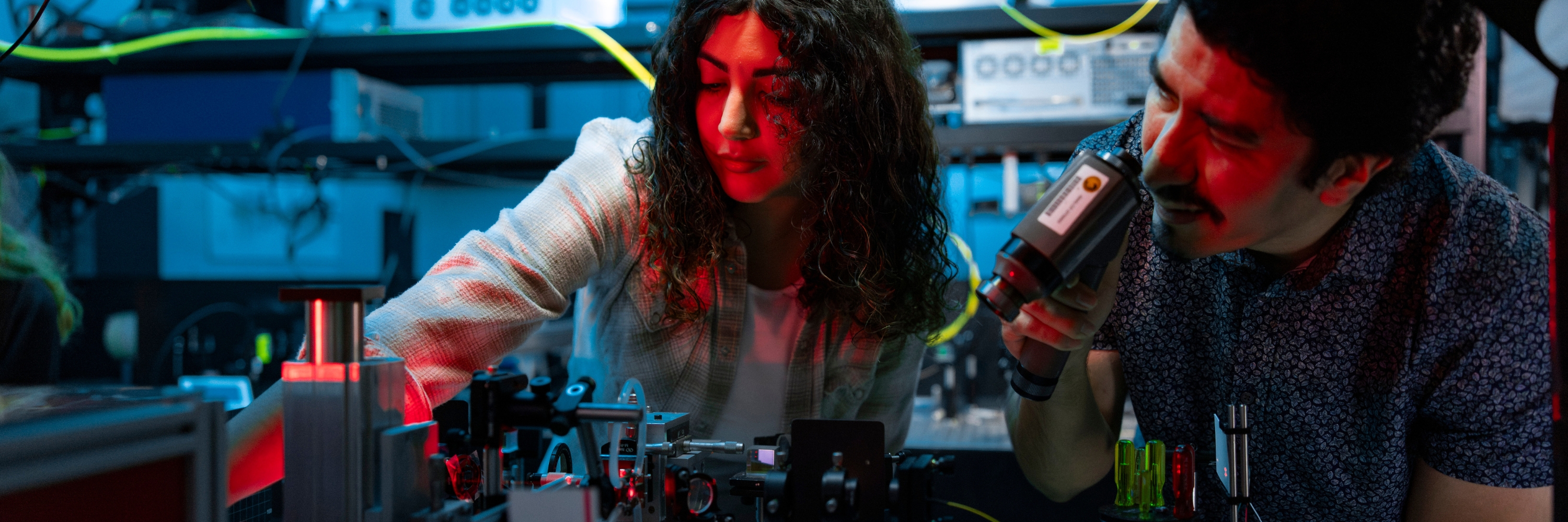 Three students in safety goggles working with lasers